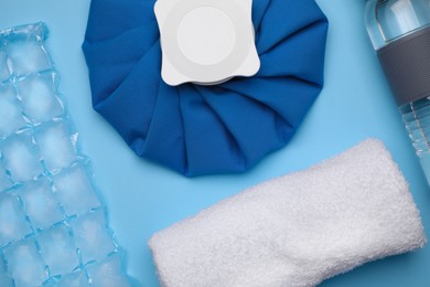 Bottle of water, cold compress, ice pack and towel on light blue background, flat lay. Heat stroke treatment Photo of Bottle of water, cold compress, ice pack and towel on light blue background, flat lay. Heat stroke treatment