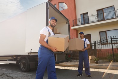 Workers unloading boxes from van outdoors. Moving service Photo of Workers unloading boxes from van outdoors. Moving service