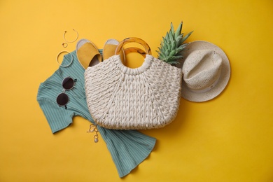 Stylish straw bag and summer accessories on yellow background, flat lay Photo of Stylish straw bag and summer accessories on yellow background, flat lay