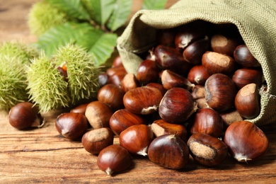 Fresh sweet edible chestnuts on wooden table, closeup Photo of Fresh sweet edible chestnuts on wooden table, closeup