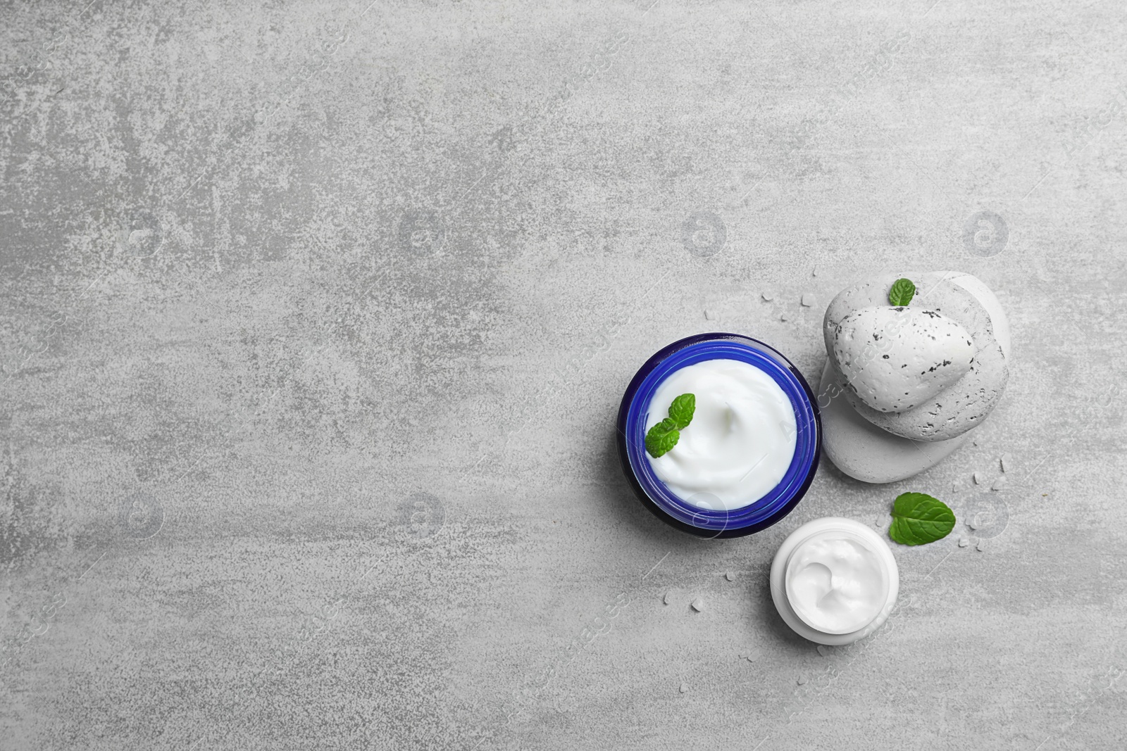 Composition with body cream in jars on grey background Photo of Composition with body cream in jars on grey background