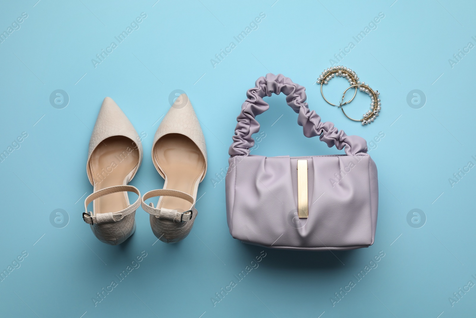 Stylish woman's bag, shoes and earrings on light blue background, flat lay Photo of Stylish woman's bag, shoes and earrings on light blue background, flat lay