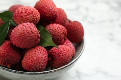 Fresh ripe lychee fruits in ceramic bowl on white table, closeup. Space for text Photo of Fresh ripe lychee fruits in ceramic bowl on white table, closeup. Space for text