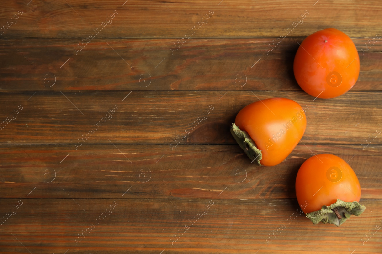 Tasty ripe persimmons on wooden table, flat lay. Space for text Photo of Tasty ripe persimmons on wooden table, flat lay. Space for text
