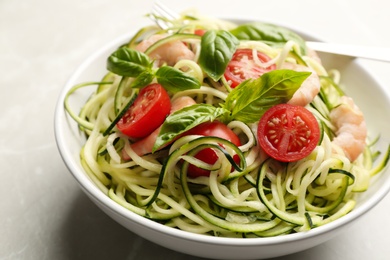 Delicious zucchini pasta with shrimps, cherry tomatoes and basil in bowl on light grey table, closeup Photo of Delicious zucchini pasta with shrimps, cherry tomatoes and basil in bowl on light grey table, closeup