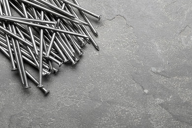 Pile of metal nails on grey stone background, flat lay. Space for text Photo of Pile of metal nails on grey stone background, flat lay. Space for text