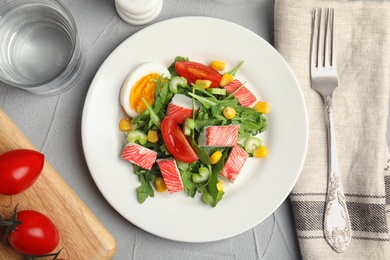 Delicious crab stick salad served on grey table, flat lay Photo of Delicious crab stick salad served on grey table, flat lay