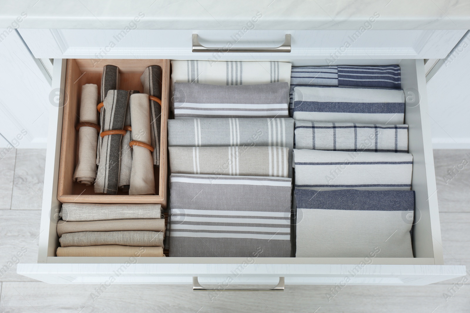 Open drawer with folded napkins and towels indoors. Order in kitchen Photo of Open drawer with folded napkins and towels indoors. Order in kitchen