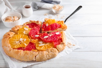 Tasty galette with citrus fruits and almond flakes on white table Photo of Tasty galette with citrus fruits and almond flakes on white table