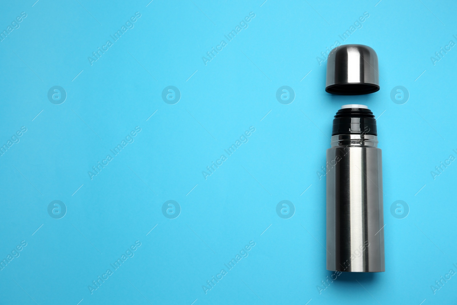 Stainless steel thermos on light blue background, top view. Space for text Photo of Stainless steel thermos on light blue background, top view. Space for text