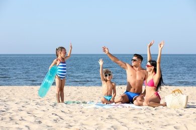 Photo of Happy family on sandy beach near sea. Summer holidays
