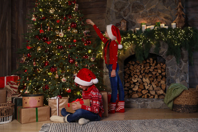 Children near beautiful Christmas tree at home Photo of Children near beautiful Christmas tree at home