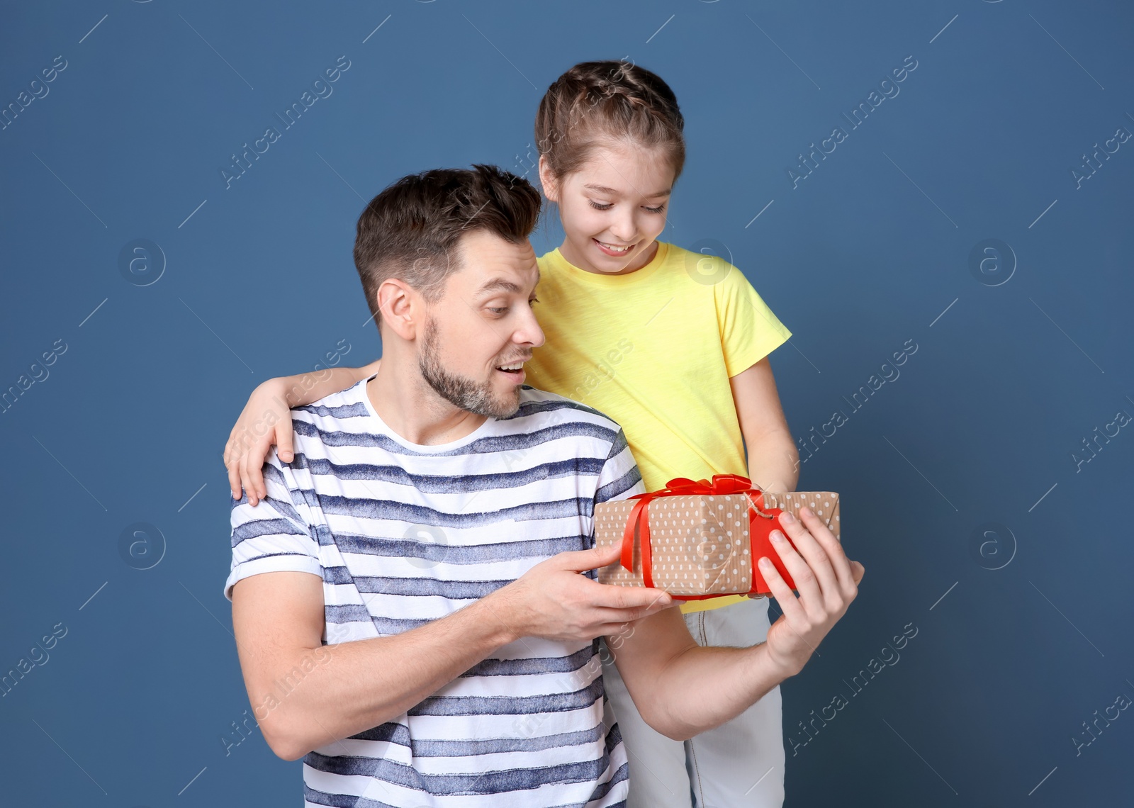 Man receiving gift for Father's Day from his daughter on color background Photo of Man receiving gift for Father's Day from his daughter on color background