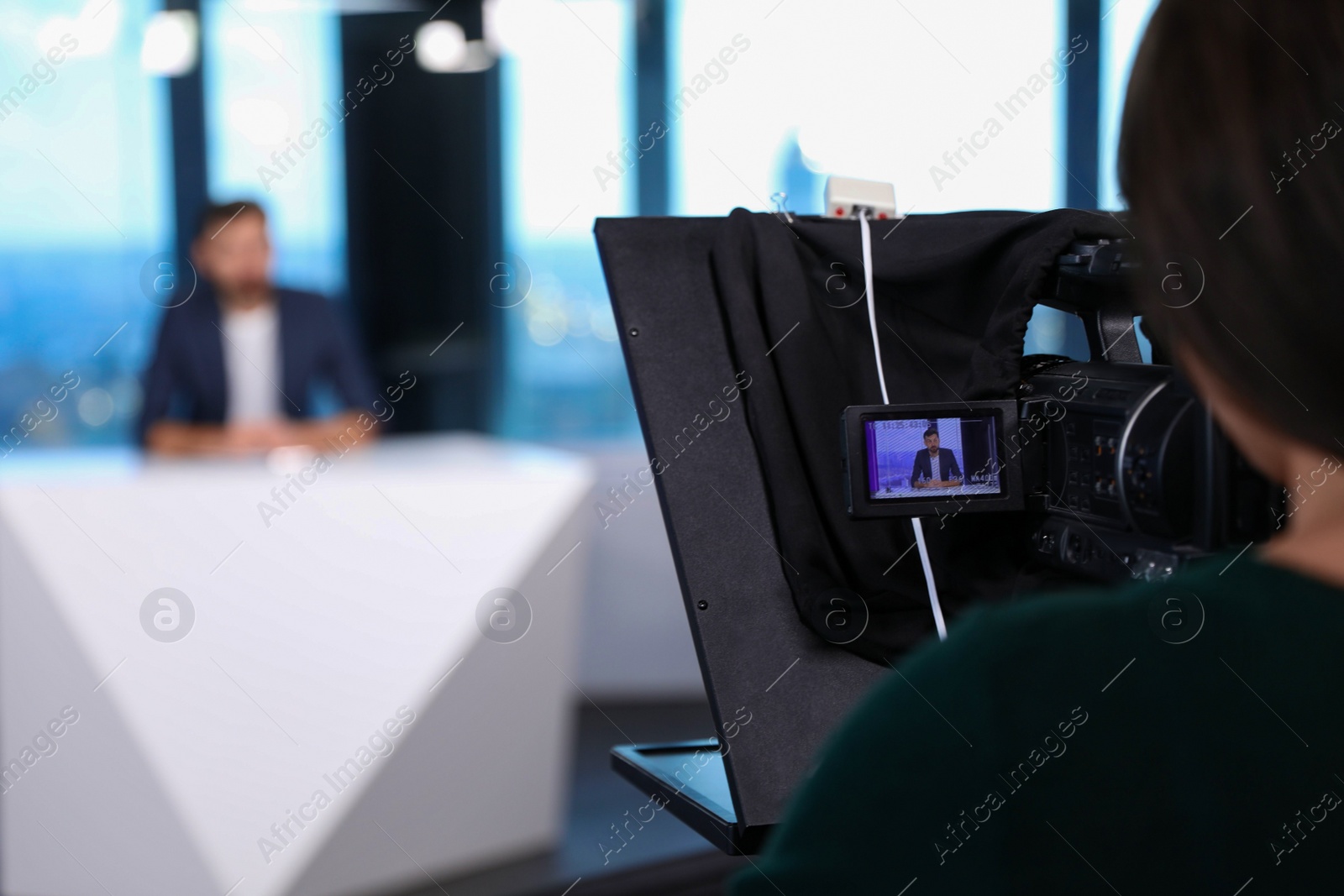 Photo of Presenter and video camera operator working in studio. News broadcasting