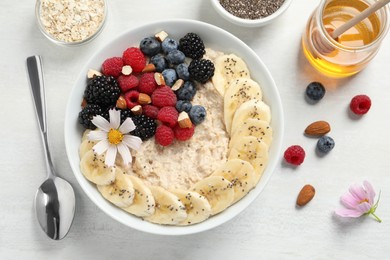 Tasty oatmeal porridge with berries, banana and chia seeds served on light wooden table, flat lay Photo of Tasty oatmeal porridge with berries, banana and chia seeds served on light wooden table, flat lay