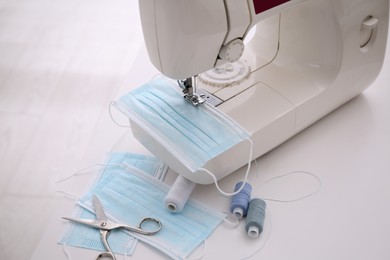 Sewing machine with disposable face mask on table, closeup Photo of Sewing machine with disposable face mask on table, closeup