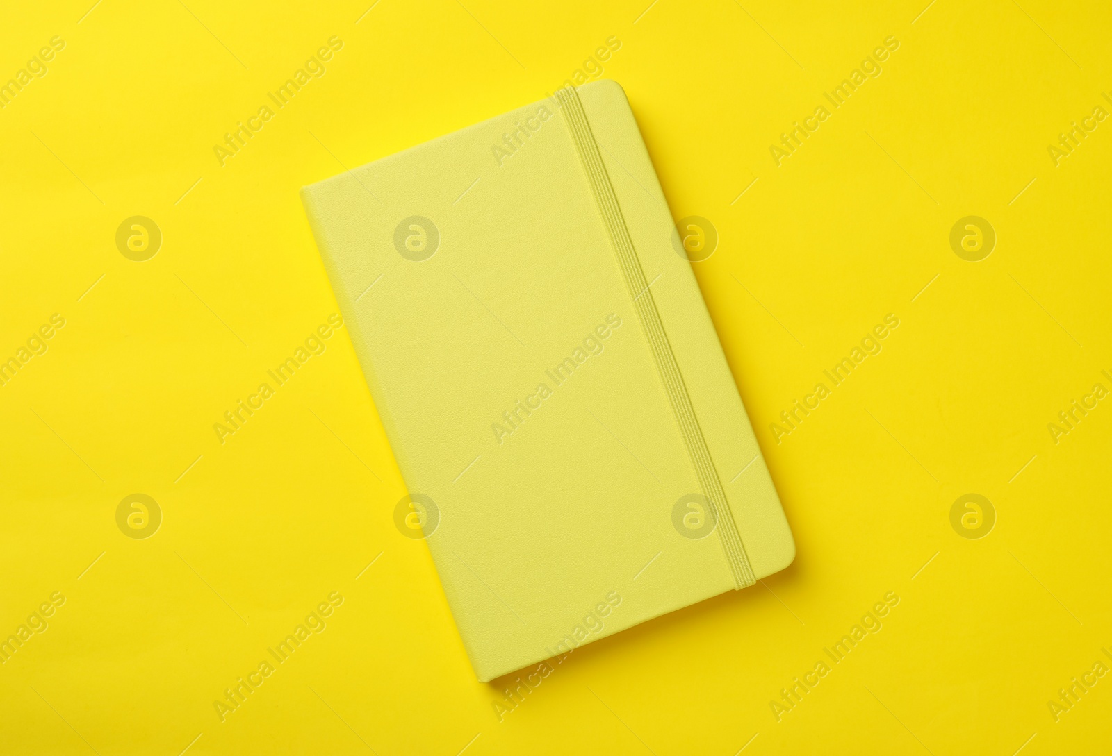 New stylish planner with hard cover on yellow background, top view Photo of New stylish planner with hard cover on yellow background, top view