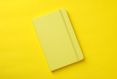 New stylish planner with hard cover on yellow background, top view Photo of New stylish planner with hard cover on yellow background, top view