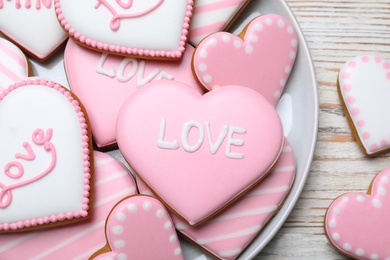 Photo of Decorated heart shaped cookies on white wooden table, flat lay. Valentine's day treat