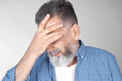 Man suffering from headache on light background Photo of Man suffering from headache on light background