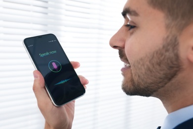 Young man using voice search on smartphone indoors, closeup Photo of Young man using voice search on smartphone indoors, closeup