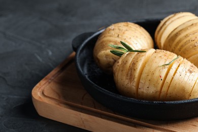 Raw Hasselback potatoes with rosemary in baking pan on dark grey table, closeup. Space for text Photo of Raw Hasselback potatoes with rosemary in baking pan on dark grey table, closeup. Space for text