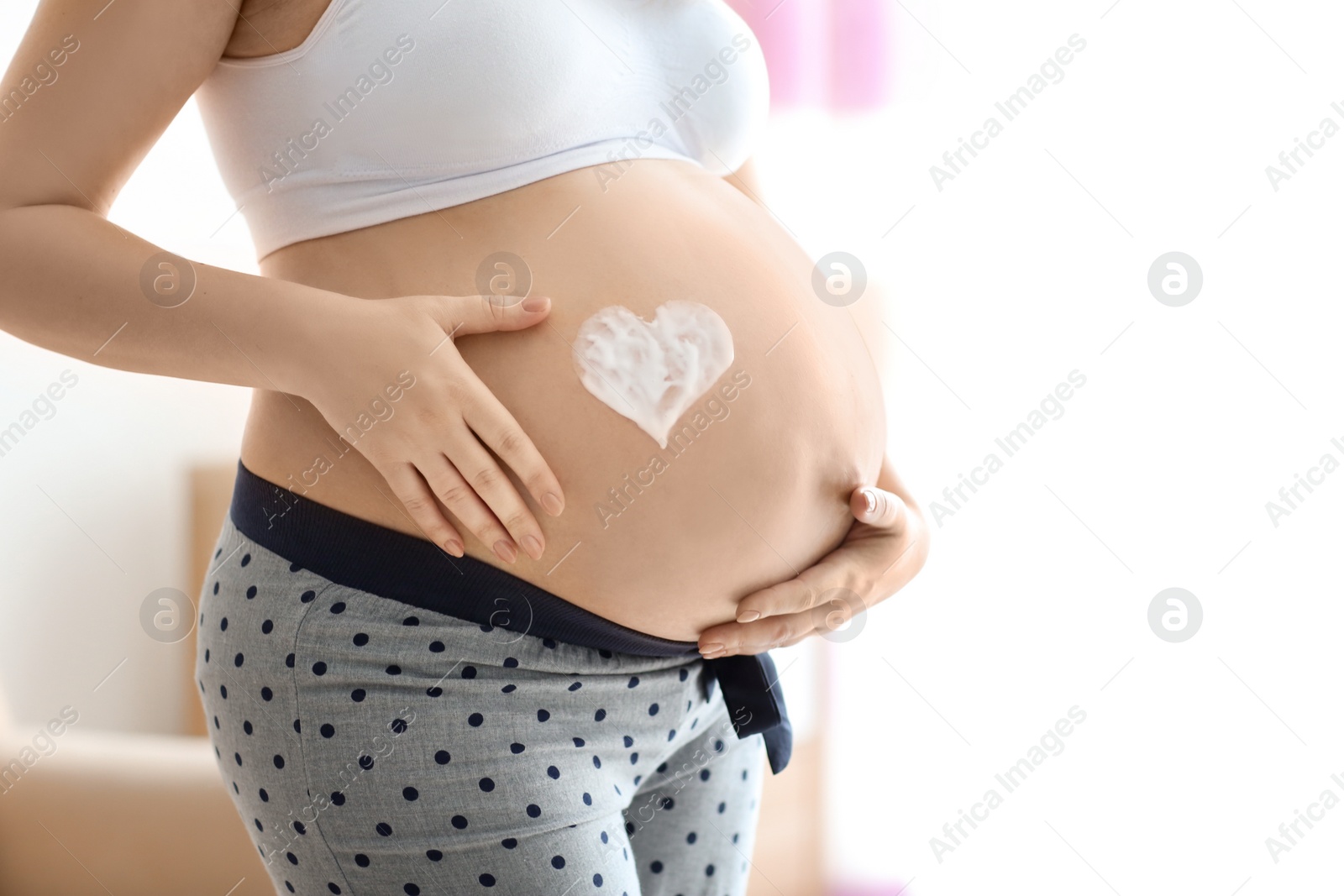 Heart painted with cream on pregnant woman's belly against blurred background, closeup Photo of Heart painted with cream on pregnant woman's belly against blurred background, closeup