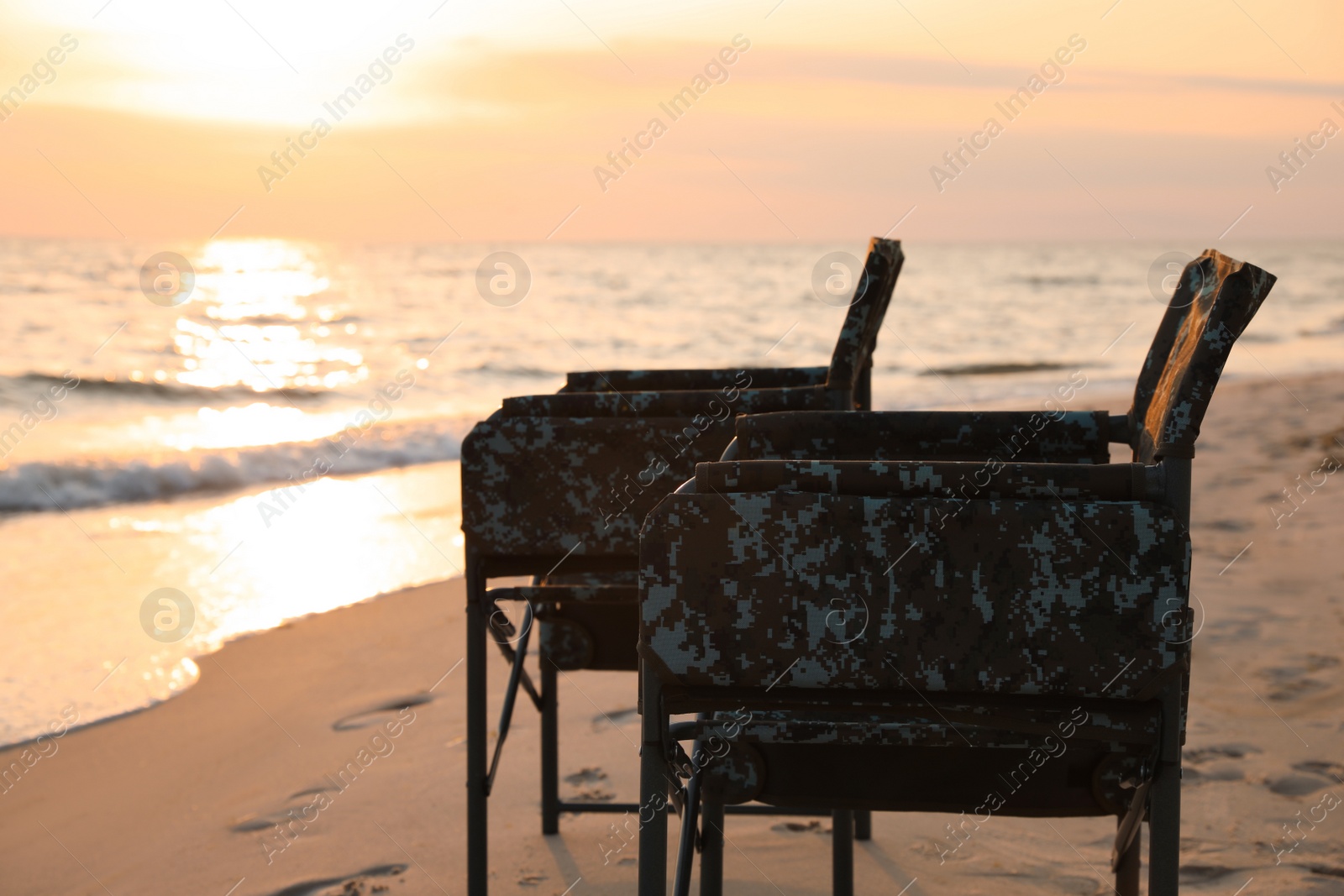 Camping chairs on sandy beach near sea Photo of Camping chairs on sandy beach near sea