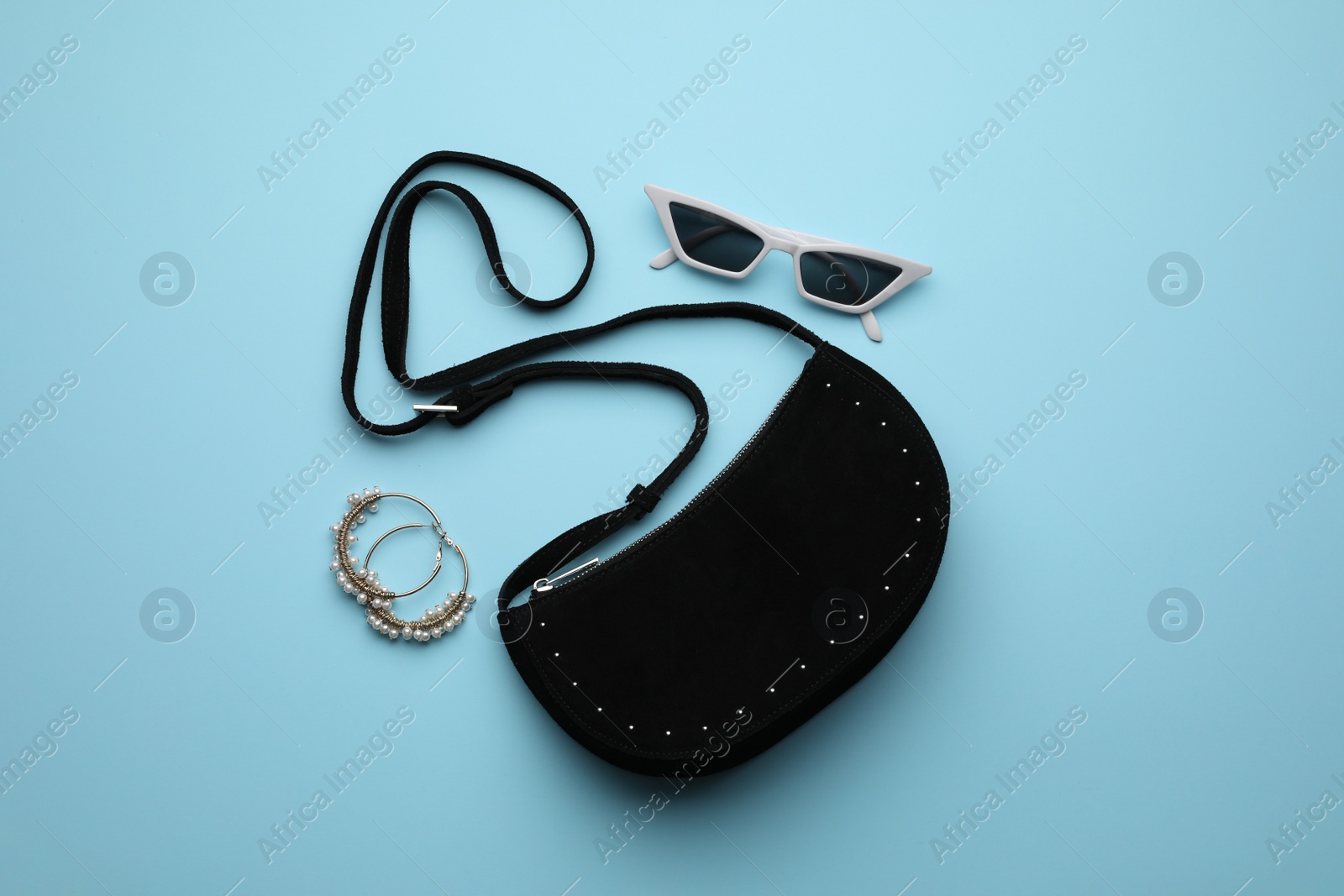 Stylish woman's bag, sunglasses and earrings on light blue background, flat lay Photo of Stylish woman's bag, sunglasses and earrings on light blue background, flat lay