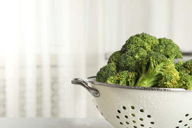 Raw green broccoli in colander on light background, closeup. Space for text Photo of Raw green broccoli in colander on light background, closeup. Space for text