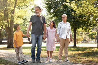 Happy grandparents with little children walking together in park Photo of Happy grandparents with little children walking together in park