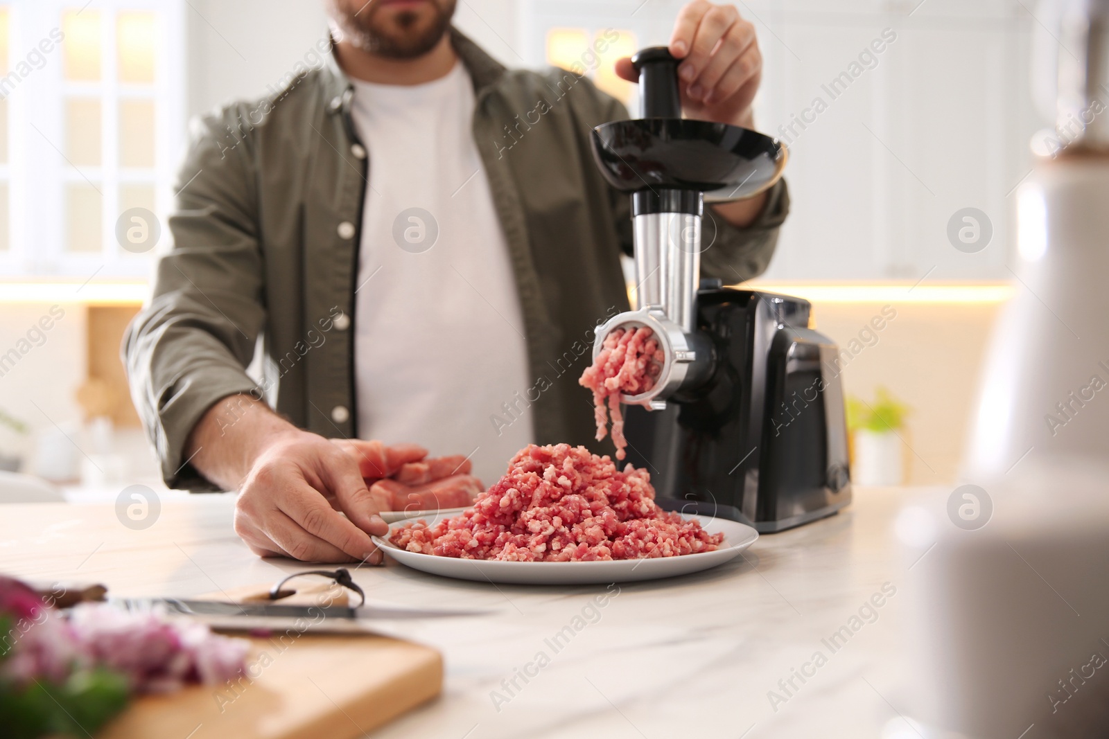 Man using modern meat grinder in kitchen, closeup Photo of Man using modern meat grinder in kitchen, closeup