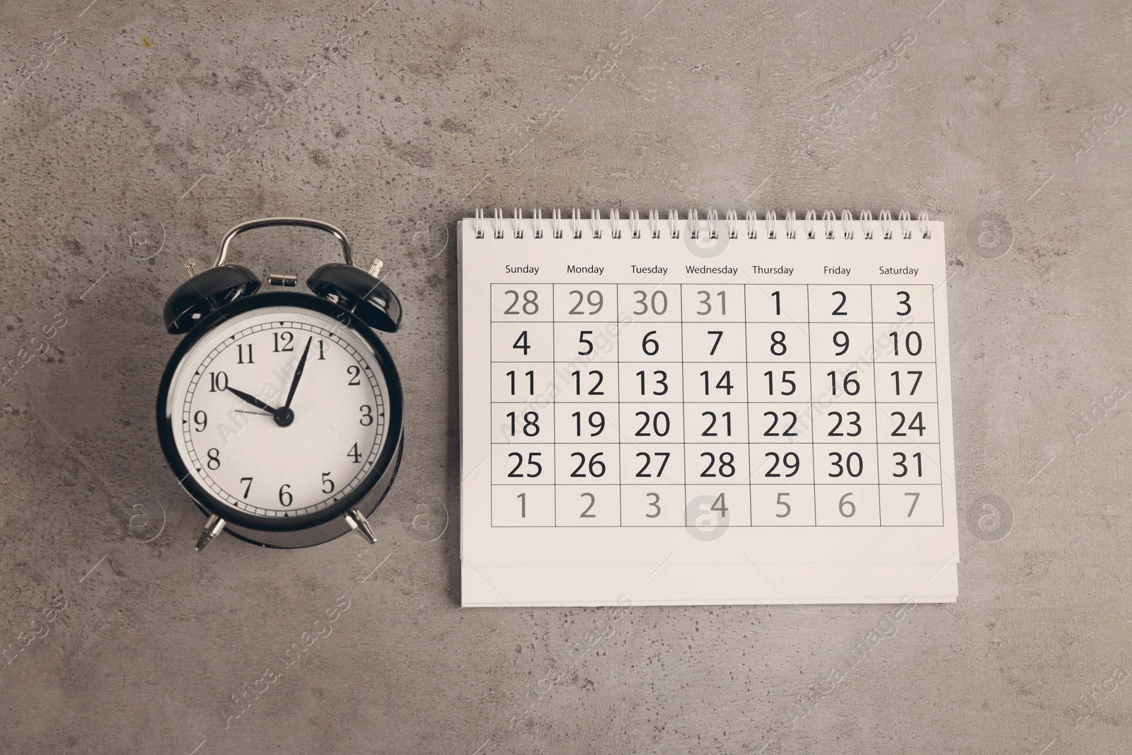 Calendar and alarm clock on grey stone background, flat lay Image of Calendar and alarm clock on grey stone background, flat lay