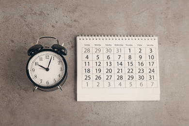 Calendar and alarm clock on grey stone background, flat lay Image of Calendar and alarm clock on grey stone background, flat lay