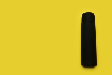 Black thermos on yellow background, top view. Space for text Photo of Black thermos on yellow background, top view. Space for text