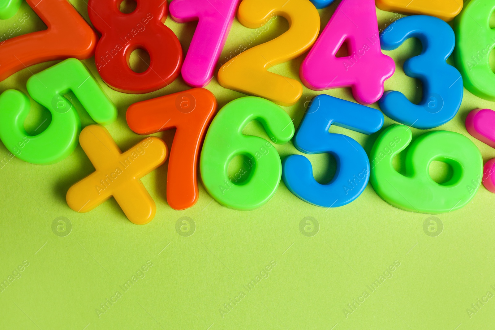 Colorful magnetic numbers on light green background, flat lay Photo of Colorful magnetic numbers on light green background, flat lay