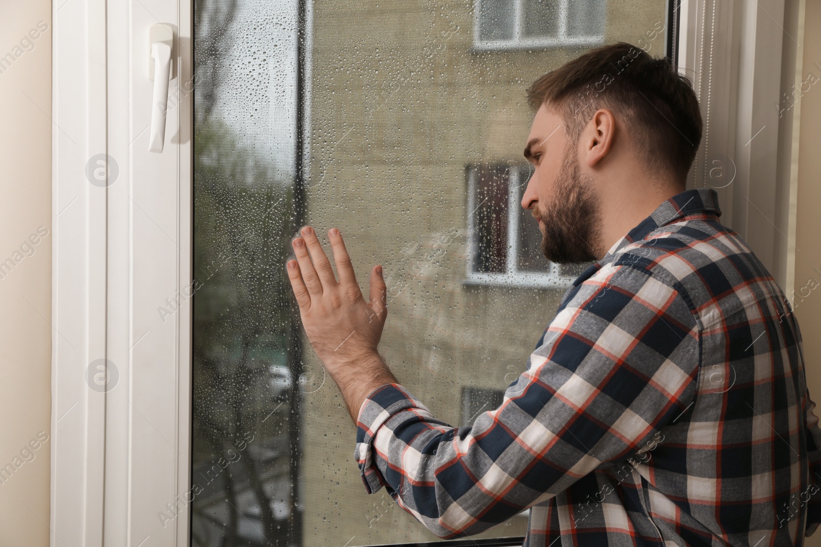 Depressed young man near window at home Photo of Depressed young man near window at home