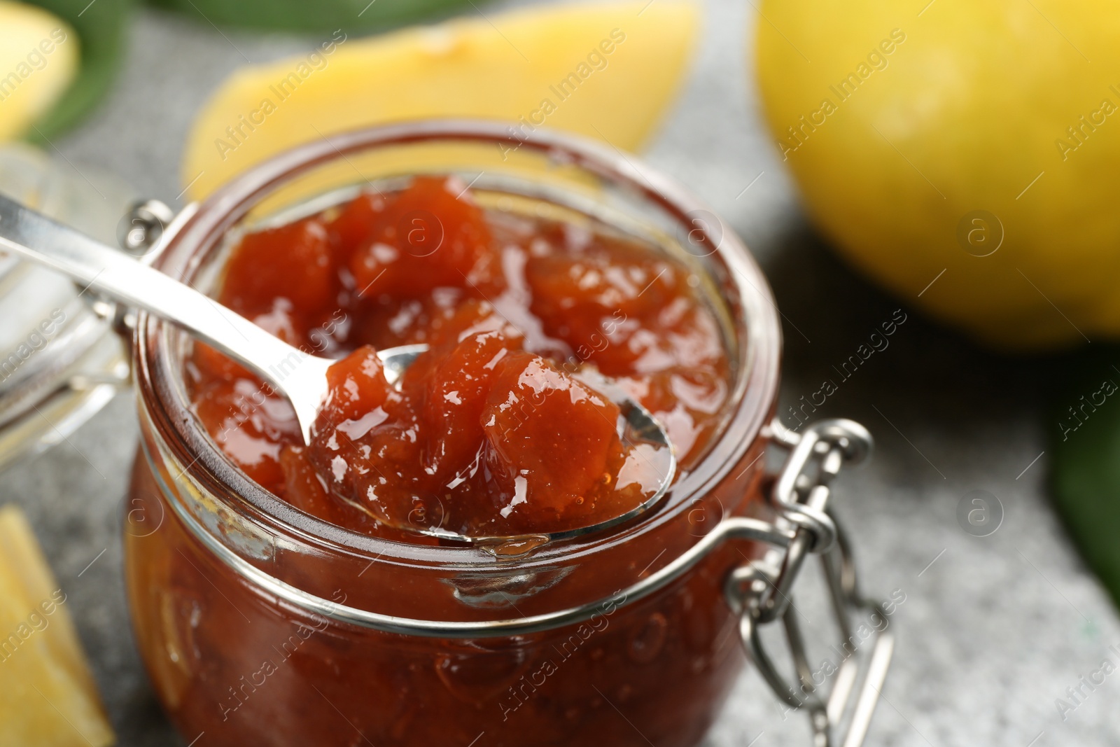 Photo of Delicious quince jam and fruits on grey table, closeup