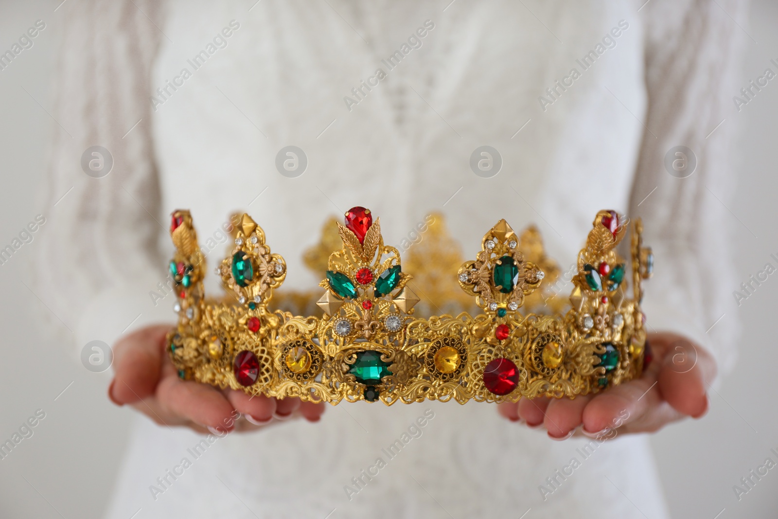Woman holding beautiful crown with gems on light background, closeup. Fantasy medieval period Photo of Woman holding beautiful crown with gems on light background, closeup. Fantasy medieval period