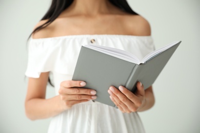 Young woman reading book on light grey background, closeup Photo of Young woman reading book on light grey background, closeup