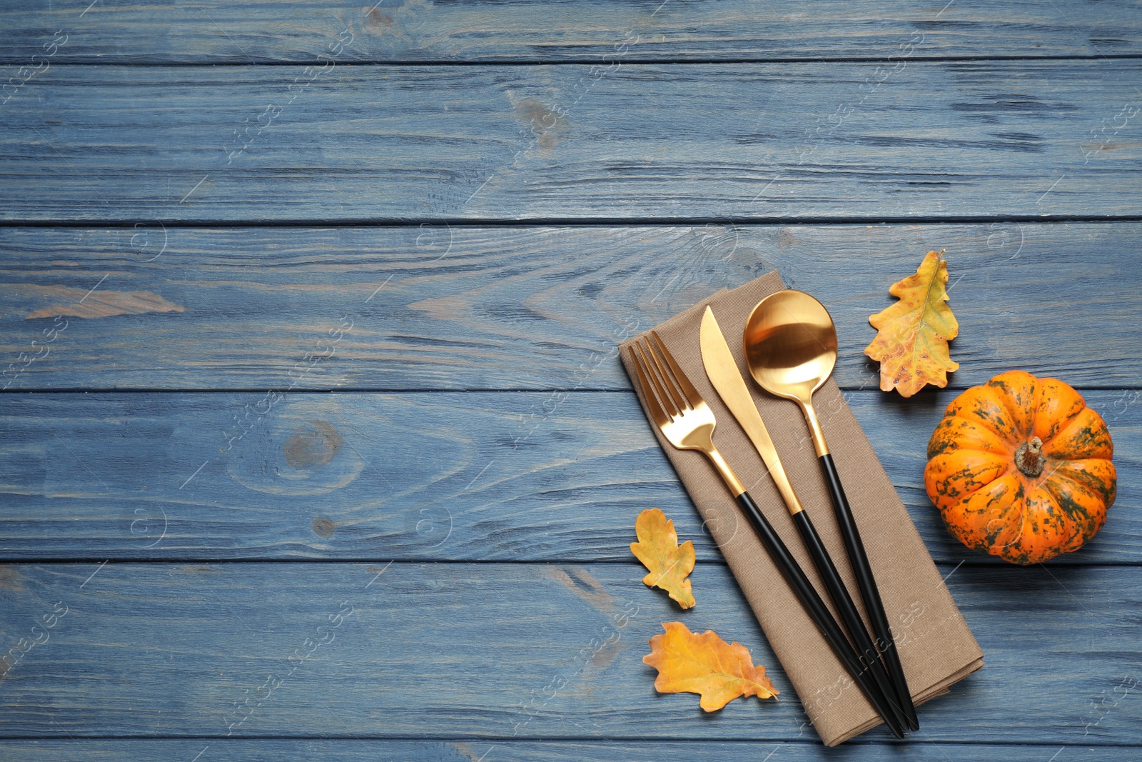Cutlery, autumn leaves and pumpkin on blue wooden table, flat lay with space for text. Thanksgiving Day Photo of Cutlery, autumn leaves and pumpkin on blue wooden table, flat lay with space for text. Thanksgiving Day