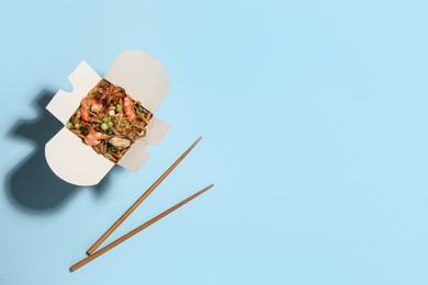 Noodle wok with chopsticks on light blue background, flat lay. Space for text Photo of Noodle wok with chopsticks on light blue background, flat lay. Space for text