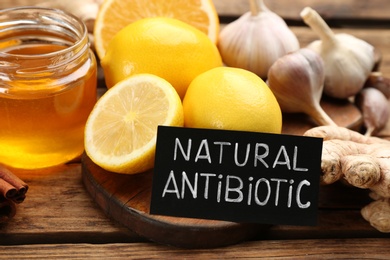 Different fresh products and card with phrase Natural Antibiotic on wooden table, closeup Photo of Different fresh products and card with phrase Natural Antibiotic on wooden table, closeup