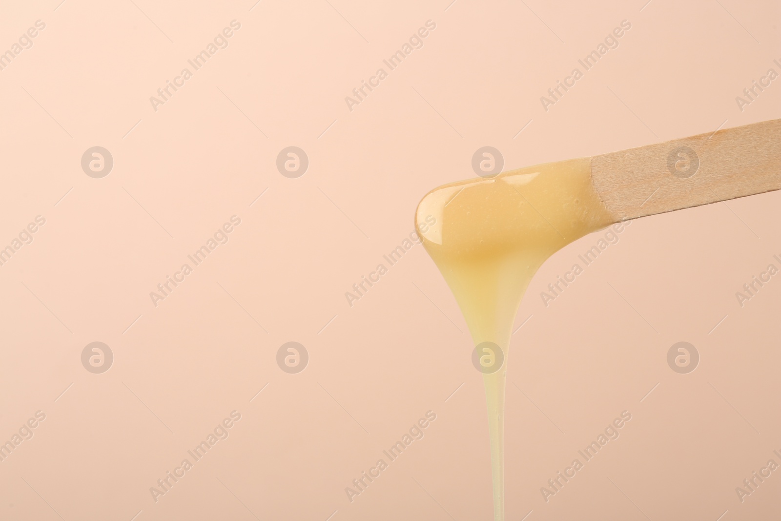 Wooden spatula with hot depilatory wax on beige background. Space for text Photo of Wooden spatula with hot depilatory wax on beige background. Space for text