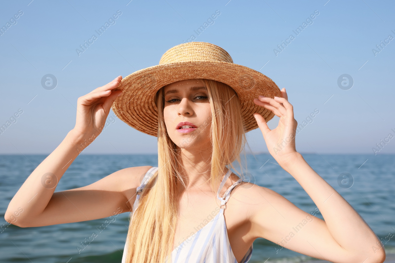 Beautiful young woman with straw hat near sea on sunny day in summer Photo of Beautiful young woman with straw hat near sea on sunny day in summer