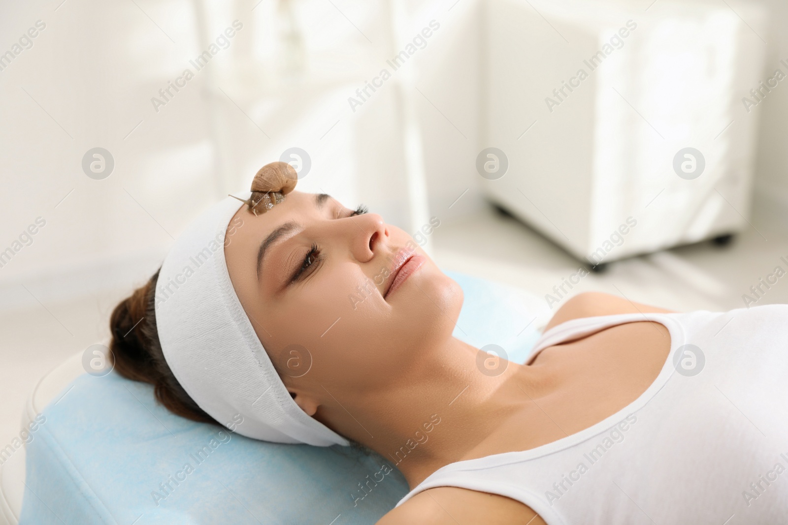 Young woman receiving snail facial massage in spa salon Photo of Young woman receiving snail facial massage in spa salon