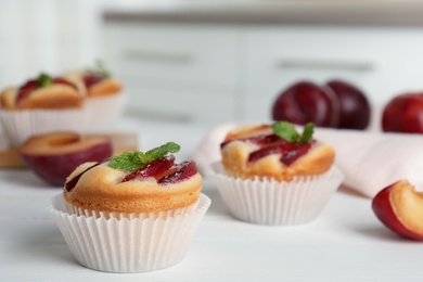 Delicious cupcakes with plums on white wooden table, closeup Photo of Delicious cupcakes with plums on white wooden table, closeup