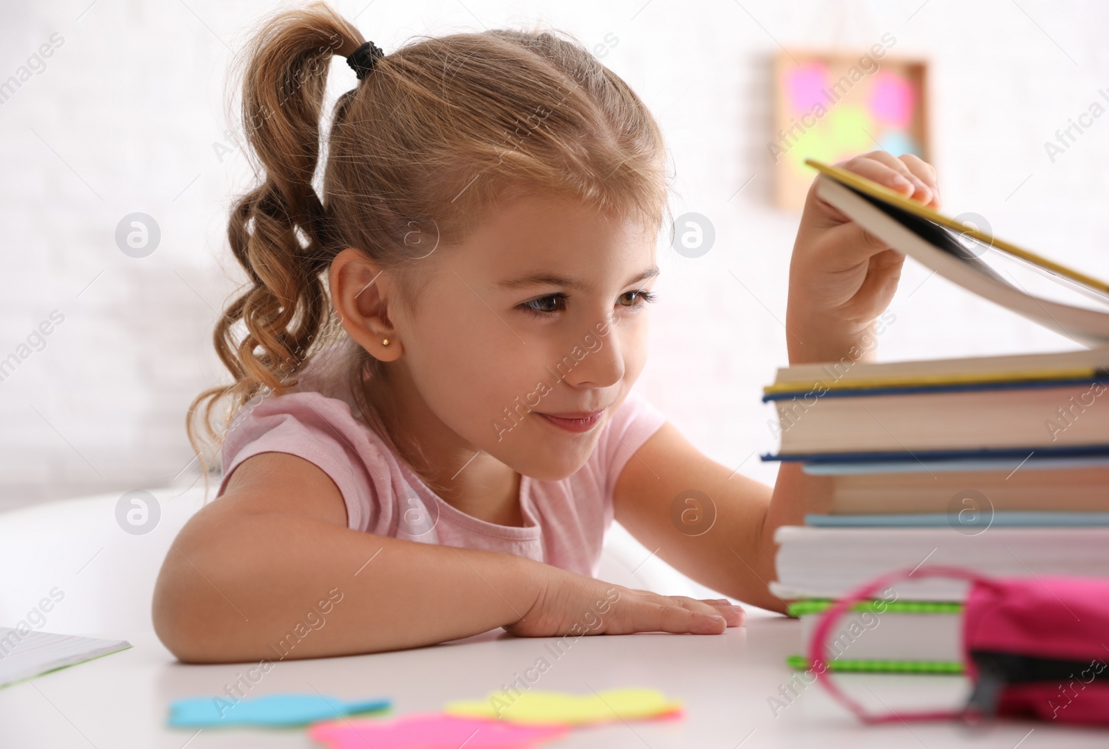 Cute little girl with books doing homework at table Photo of Cute little girl with books doing homework at table