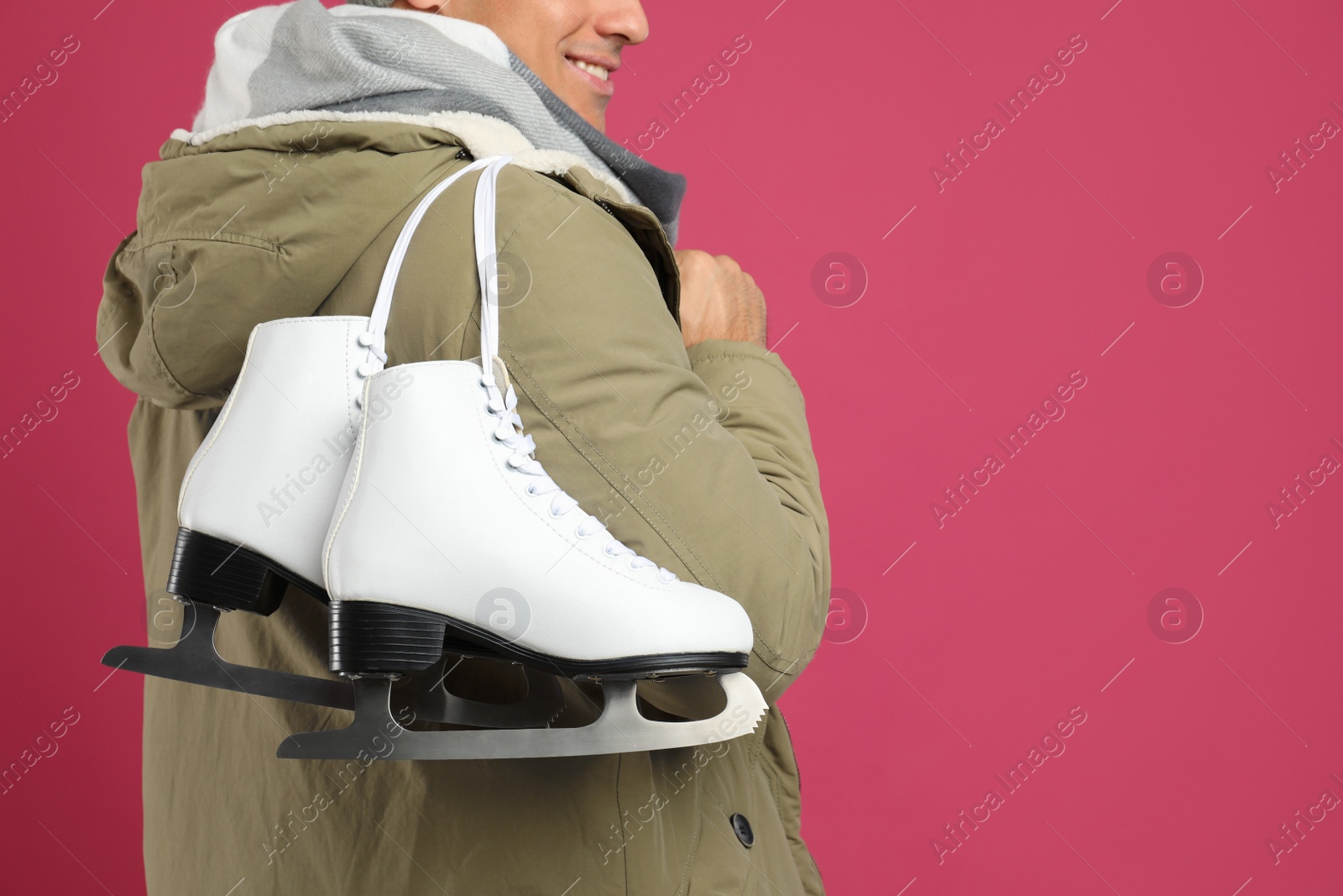 Happy man with ice skates on pink background, closeup. Space for text Photo of Happy man with ice skates on pink background, closeup. Space for text