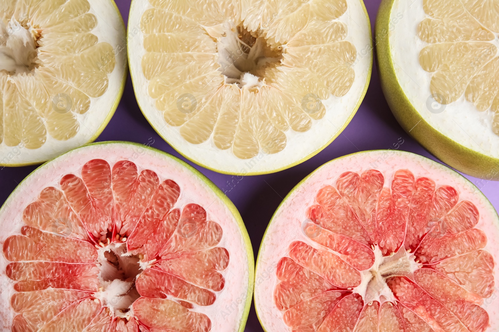 Fresh cut pomelo fruits on lilac background, flat lay Photo of Fresh cut pomelo fruits on lilac background, flat lay